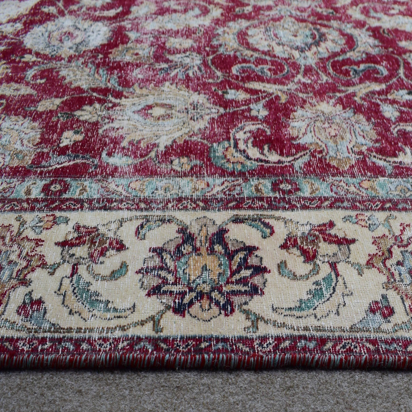 Close up of Persian rug border with ivory guard stripes and colorful floral motifs
