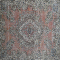 Close up of distressed Persian rug showing central medallion with faded blue and ivory floral motifs