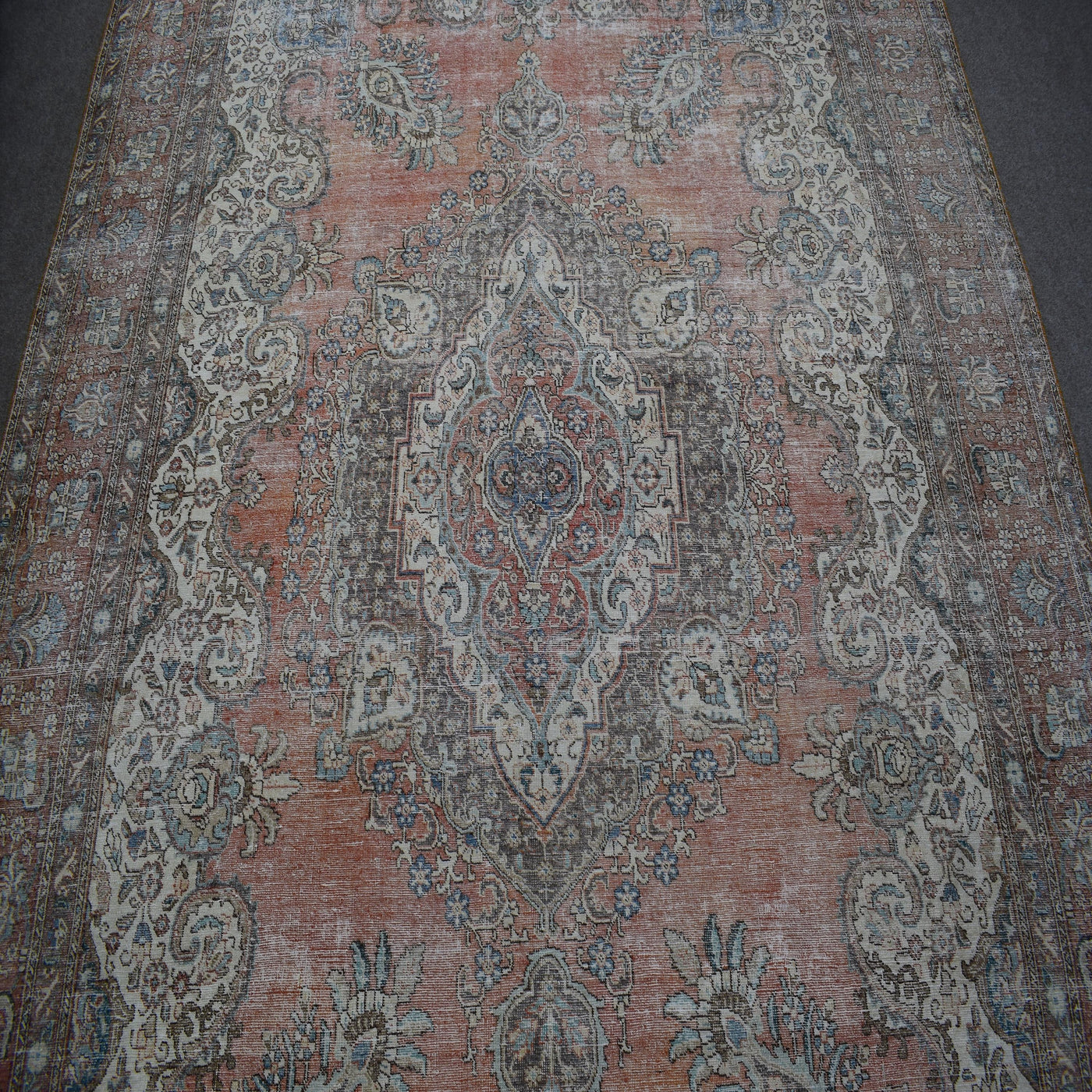 Detailed view of vintage Persian rug pattern featuring intricate floral medallion on muted terracotta background