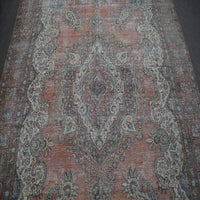 Detailed view of vintage Persian rug pattern featuring intricate floral medallion on muted terracotta background