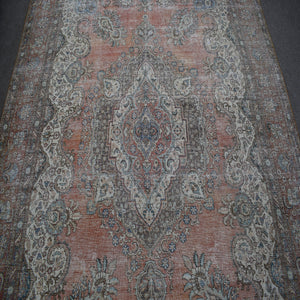 Detailed view of vintage Persian rug pattern featuring intricate floral medallion on muted terracotta background