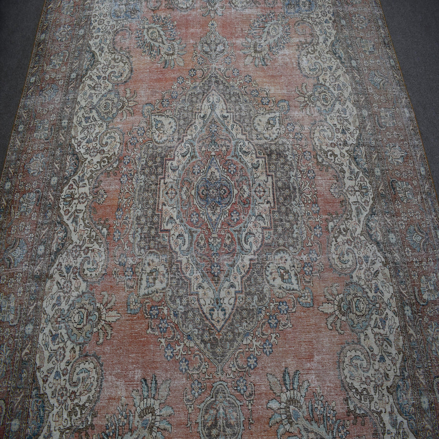 Detailed view of vintage Persian rug pattern featuring intricate floral medallion on muted terracotta background