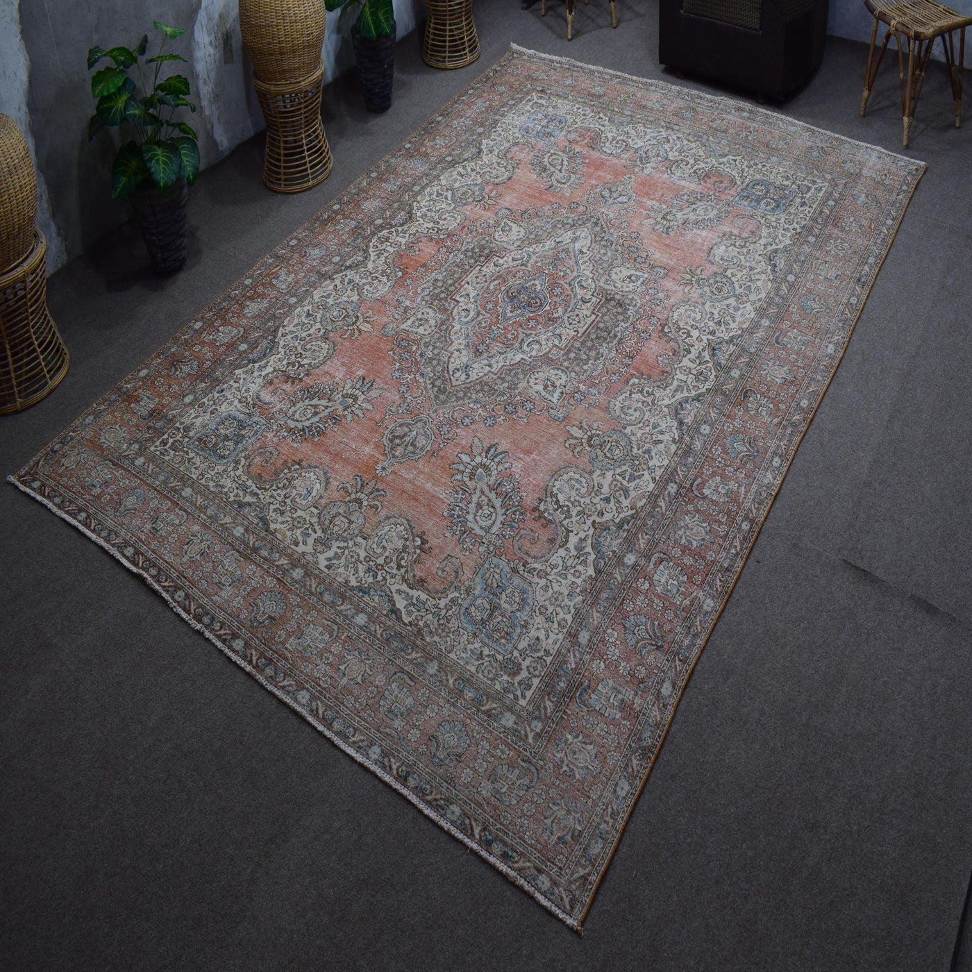 Hand knotted Persian rug photographed at an angle showing overall medallion design and faded vintage palette
