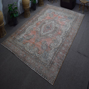 Hand knotted Persian rug photographed at an angle showing overall medallion design and faded vintage palette