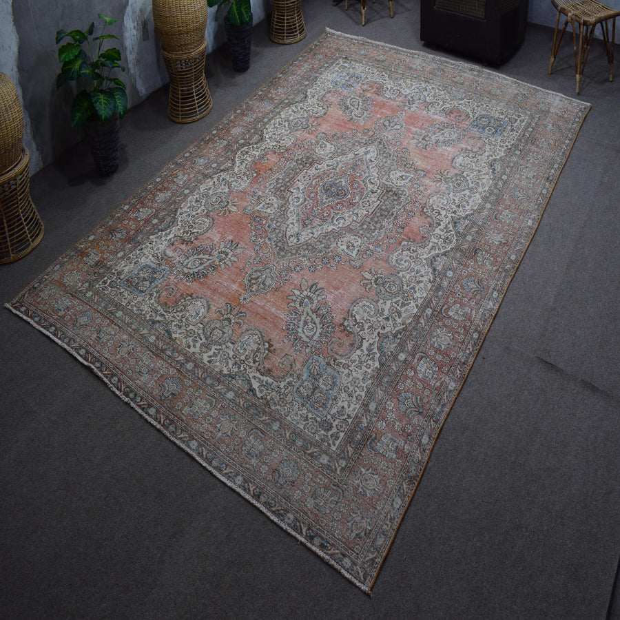 Hand knotted Persian rug photographed at an angle showing overall medallion design and faded vintage palette