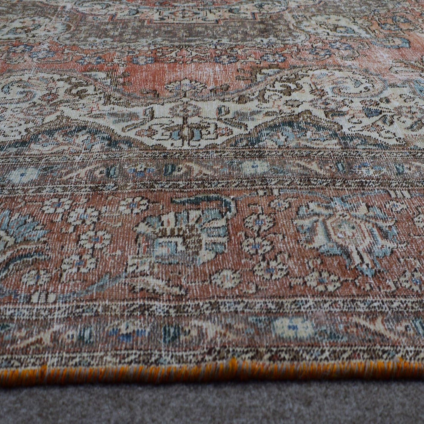Macro detail of vintage Persian rug pattern highlighting worn floral elements and wool texture
