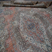 Close up of Persian rug medallion area showing intricate floral patterns in faded terracotta and blue