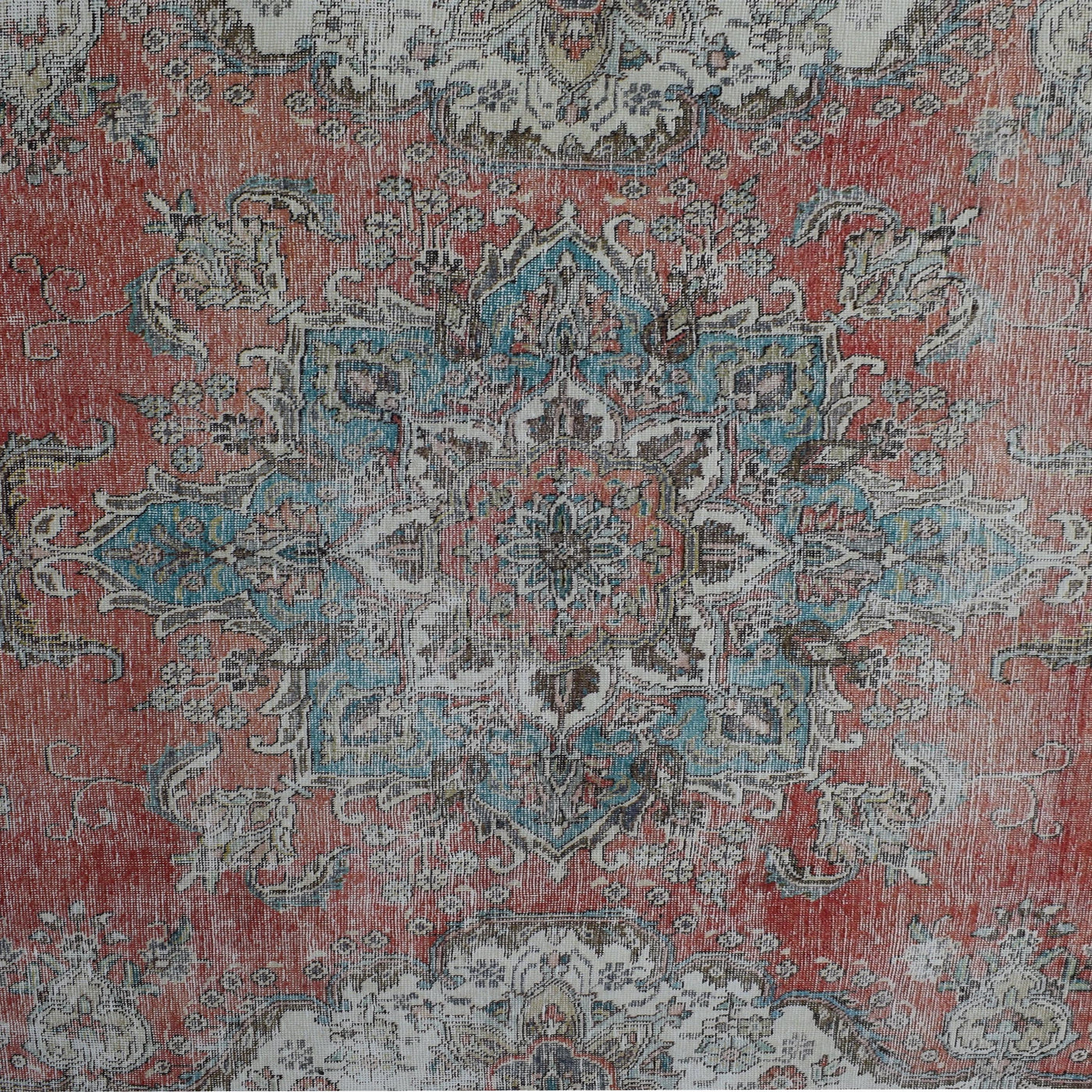 Detailed view of vintage Persian rug pattern featuring intricate floral medallion on coral red background