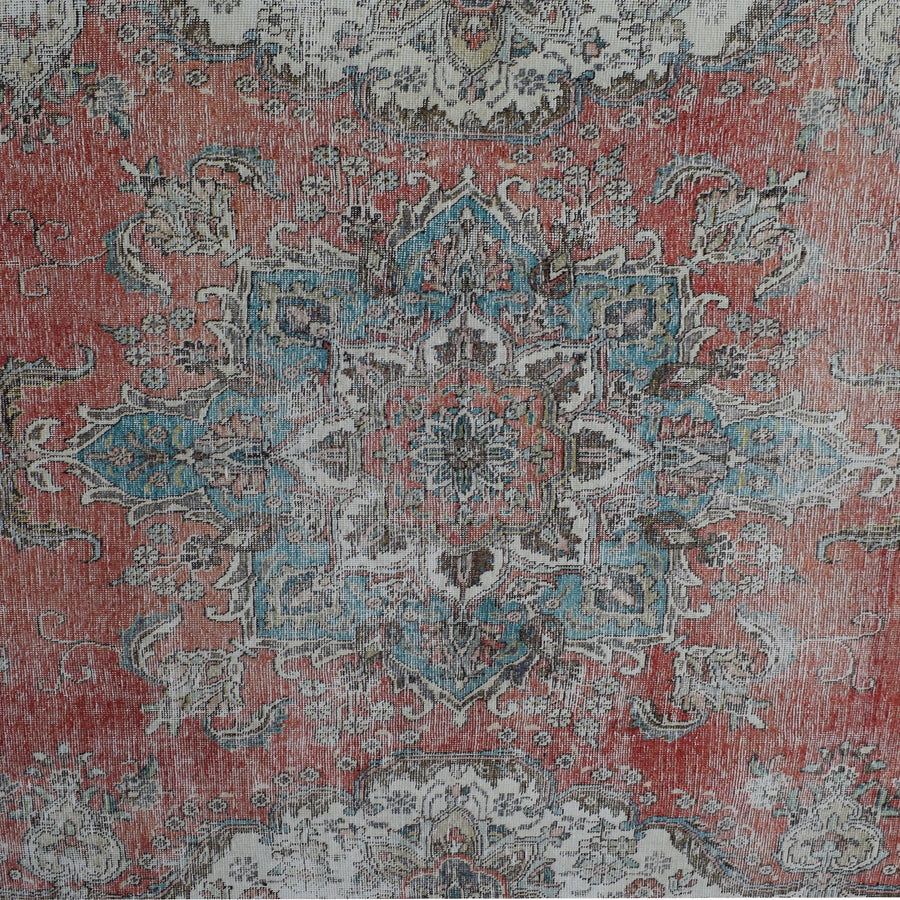 Detailed view of vintage Persian rug pattern featuring intricate floral medallion on coral red background
