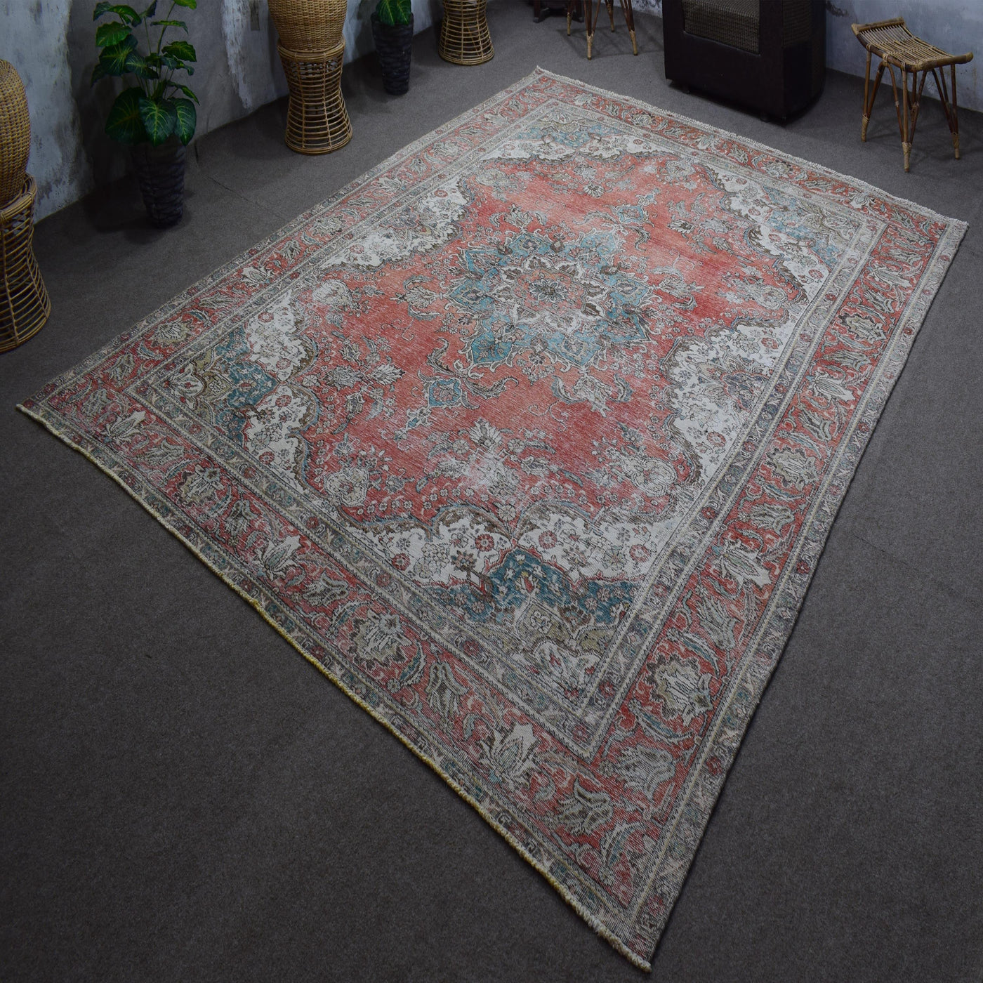 Hand knotted Persian rug photographed at an angle showing overall medallion design and distressed vintage palette