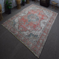 Hand knotted Persian rug photographed at an angle showing overall medallion design and distressed vintage palette