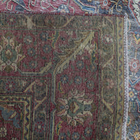 Detailed view of distressed Persian rug pattern with worn floral motifs and muted vintage tones