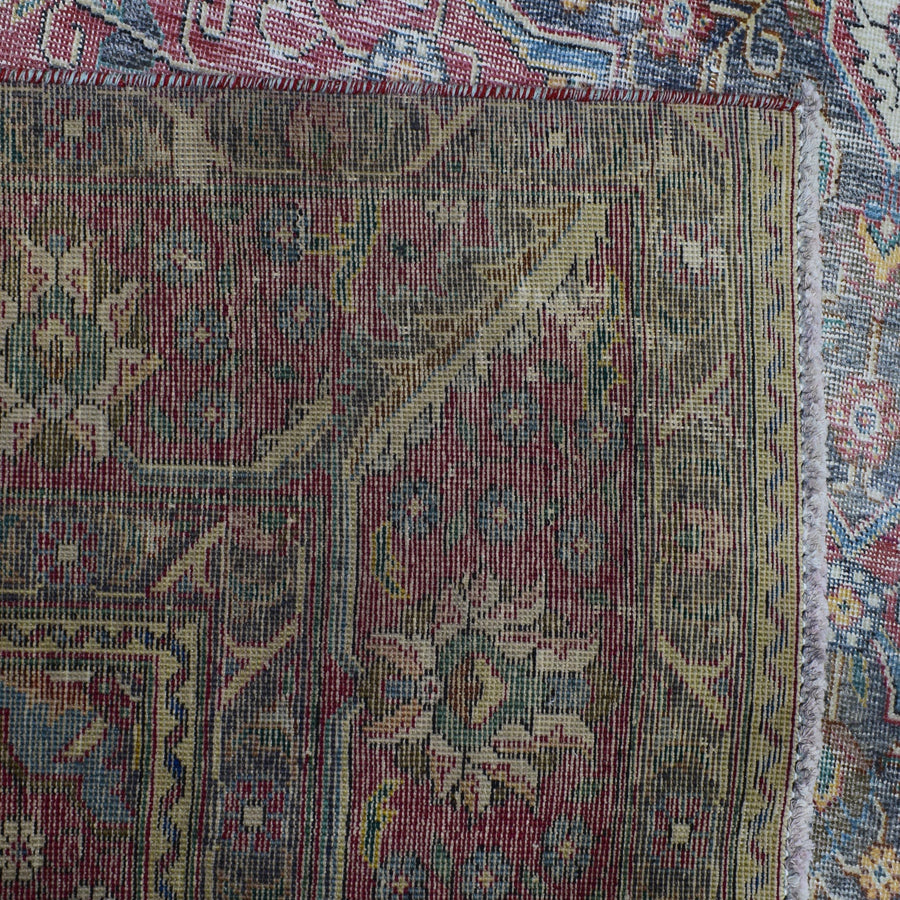 Detailed view of distressed Persian rug pattern with worn floral motifs and muted vintage tones