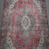 Close up of distressed Persian rug showing faded central medallion with ivory and blue floral motifs