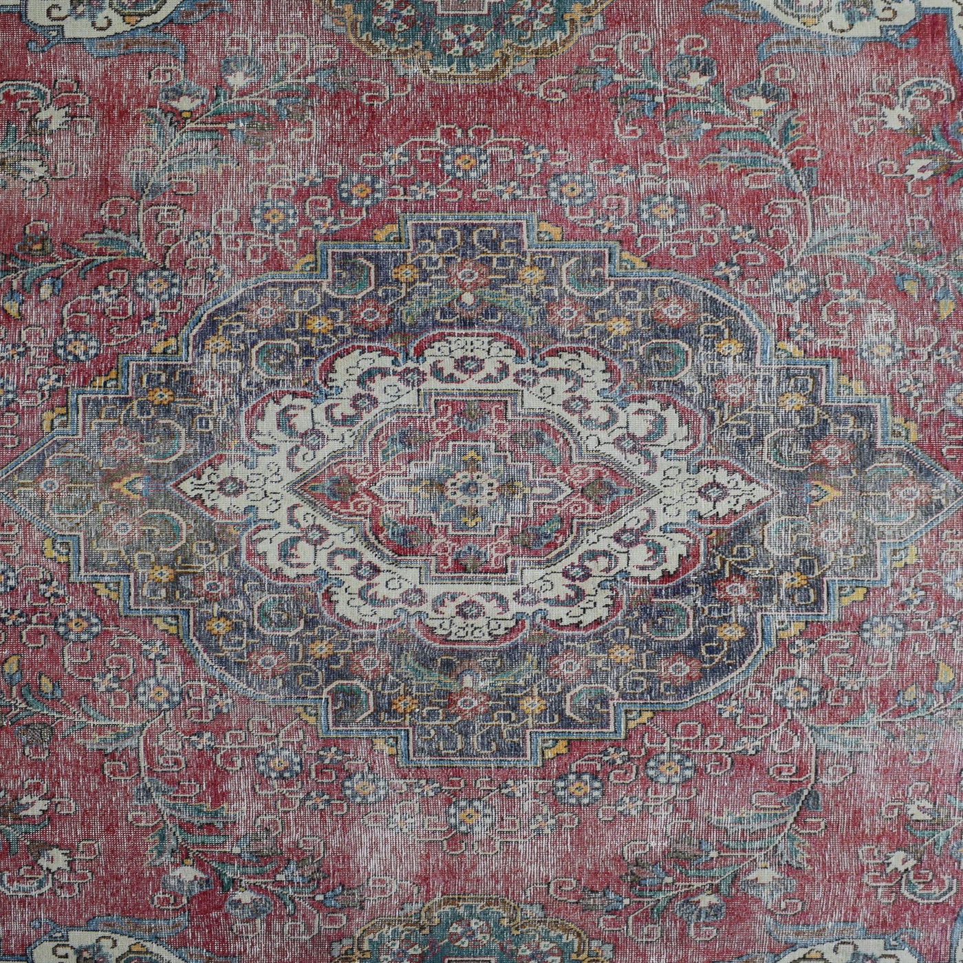 Detailed view of vintage Persian rug medallion featuring intricate floral patterns on a distressed red background