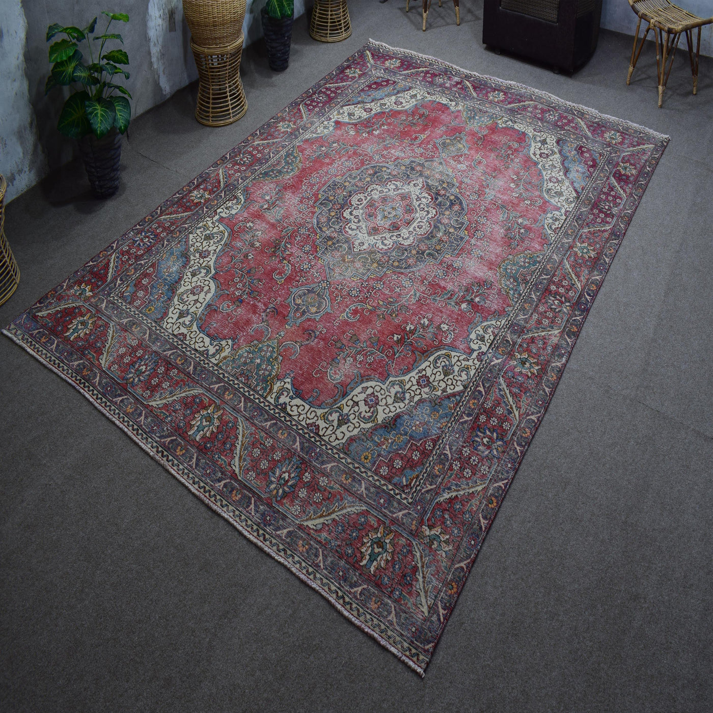 Hand knotted Persian rug photographed at an angle showing overall medallion layout and distressed vintage palette