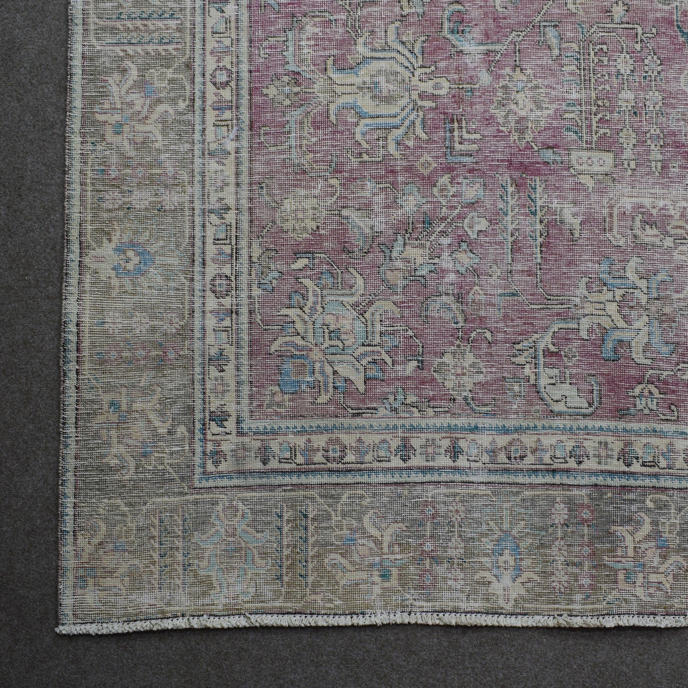 Corner detail of Persian rug with decorative floral border and aged vintage patina