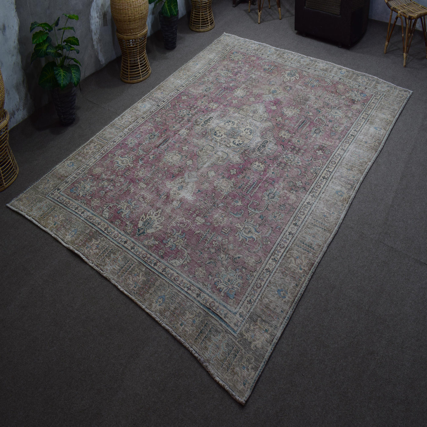 Hand knotted Persian rug photographed at an angle showing overall distressed pattern and muted color palette