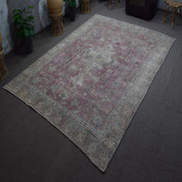 Hand knotted Persian rug photographed at an angle showing overall distressed pattern and muted color palette