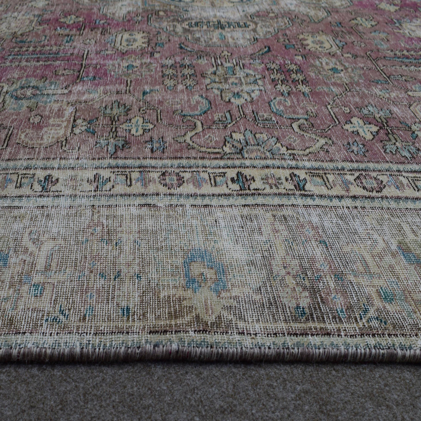Macro close up of vintage Persian rug pile showing worn wool texture and faded pattern