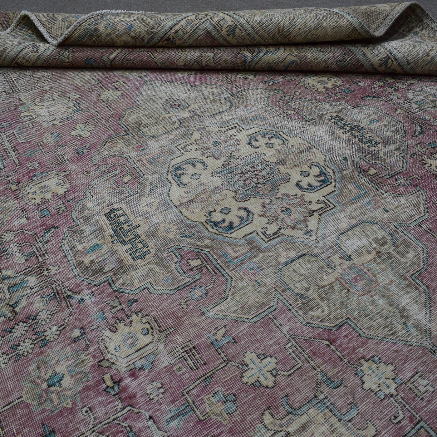Detailed view of Persian rug medallion highlighting intricate floral design and distressed surface