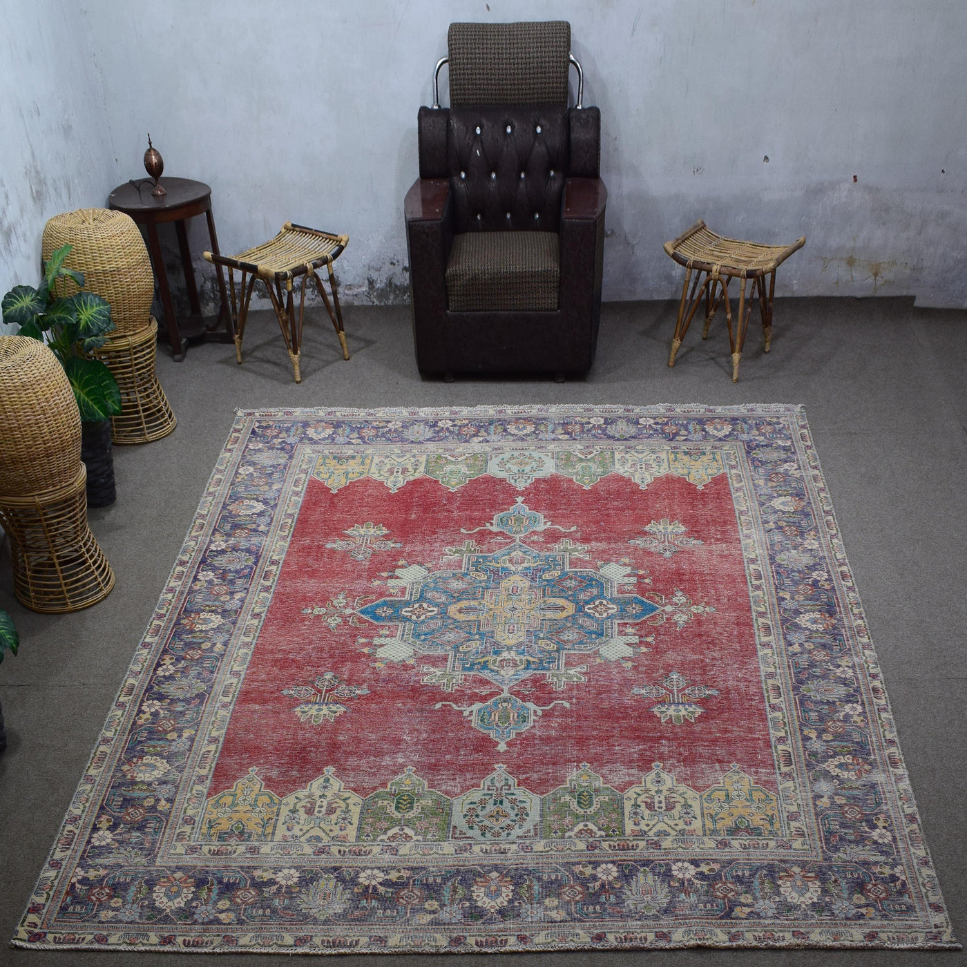 Large distressed vintage Persian rug 288x375 cm styled in interior showing red background and ornate blue medallion