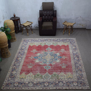 Large distressed vintage Persian rug 288x375 cm styled in interior showing red background and ornate blue medallion