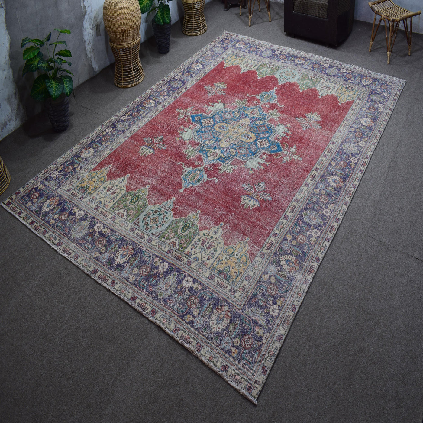 Hand knotted Persian rug photographed at an angle showing overall medallion layout and distressed red tones