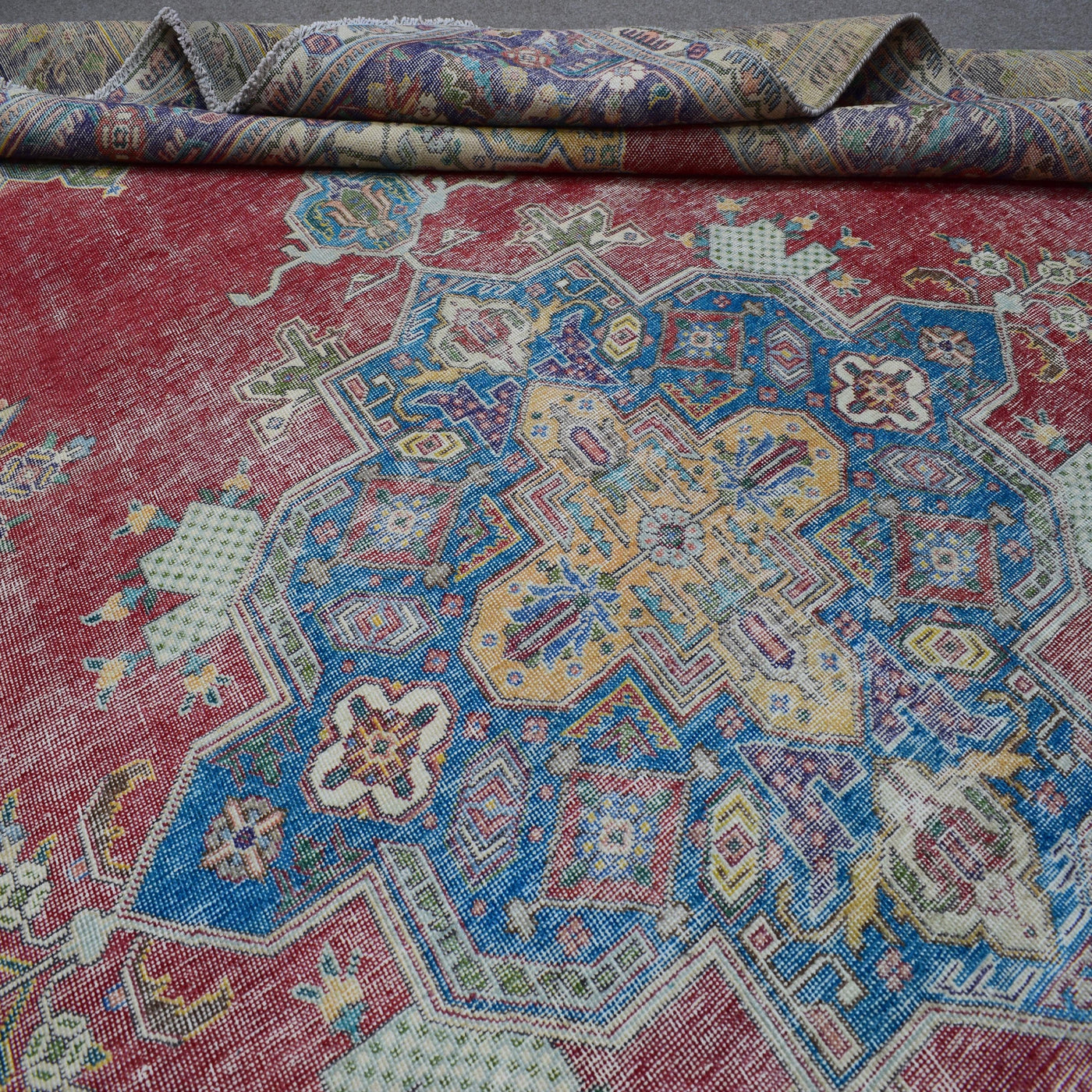 Detailed view of vintage Persian rug pattern with faded red field and blue ornamental motifs