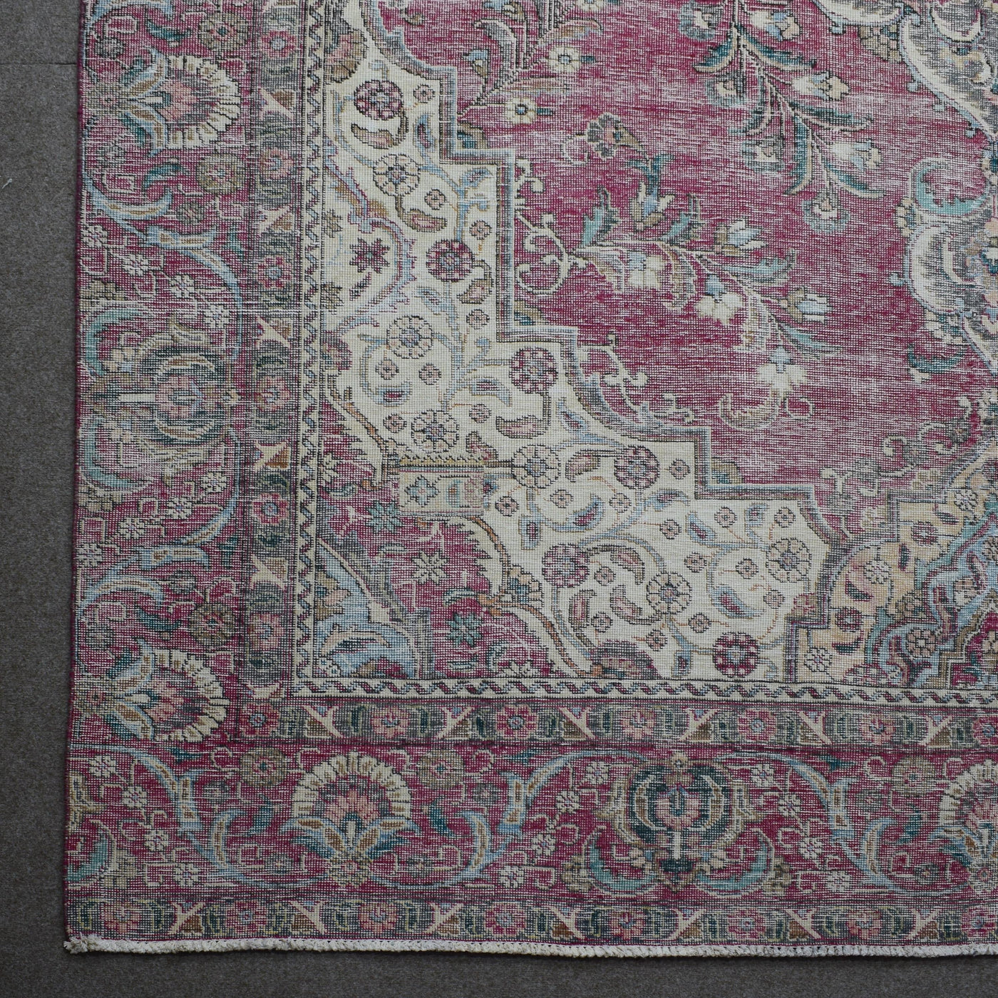 Corner detail of Persian rug with decorative floral border and aged vintage patina