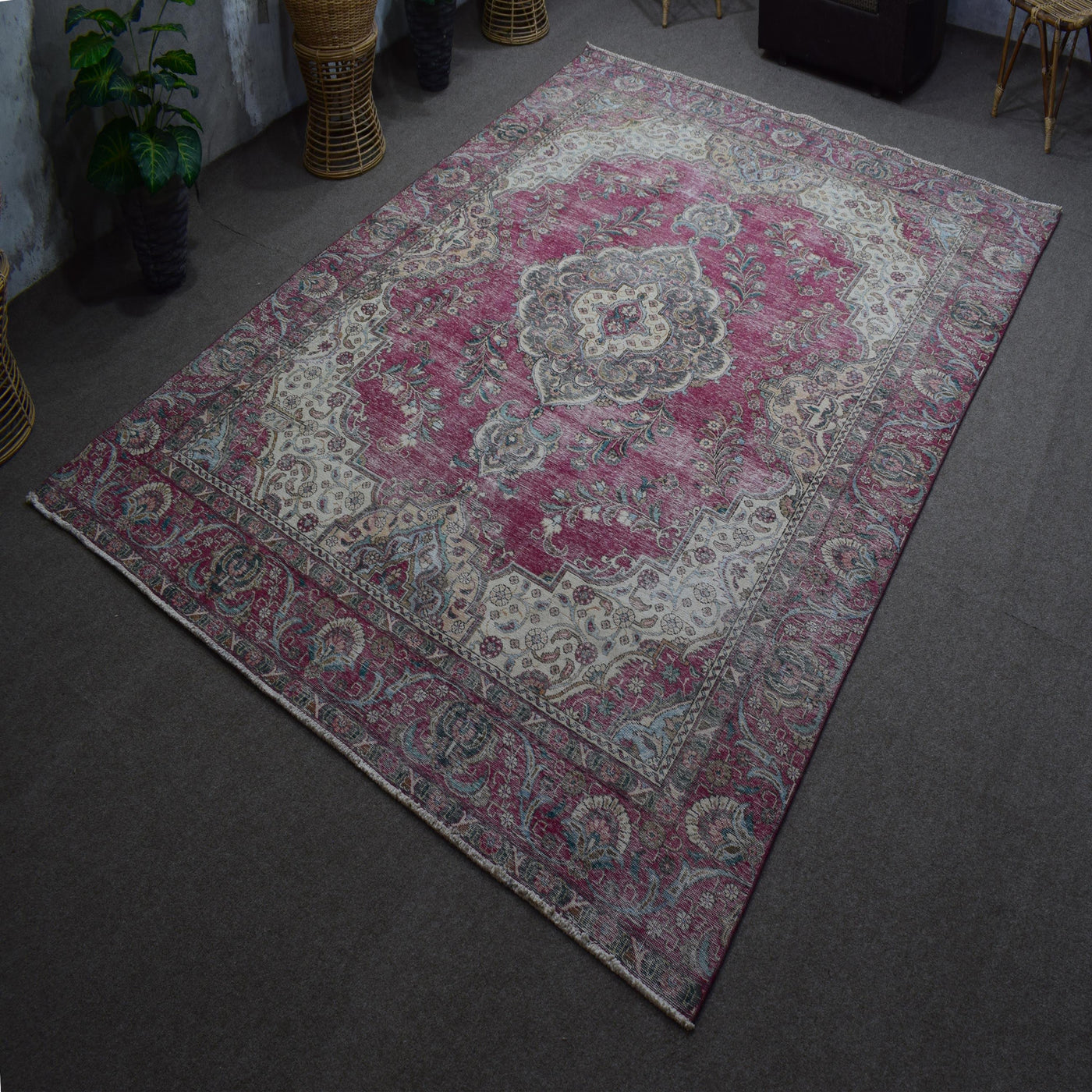 Hand knotted Persian rug photographed at an angle showing overall medallion layout and distressed color palette