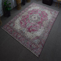 Hand knotted Persian rug photographed at an angle showing overall medallion layout and distressed color palette