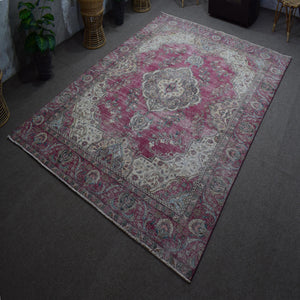 Hand knotted Persian rug photographed at an angle showing overall medallion layout and distressed color palette