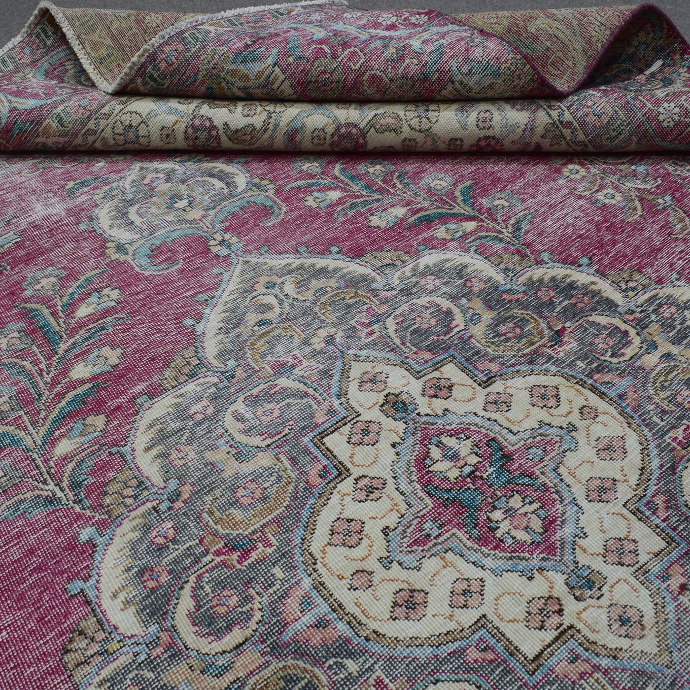 Detailed view of distressed Persian rug pattern with faded rose field and ornamental motifs