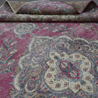 Detailed view of distressed Persian rug pattern with faded rose field and ornamental motifs