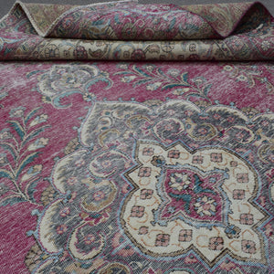 Detailed view of distressed Persian rug pattern with faded rose field and ornamental motifs