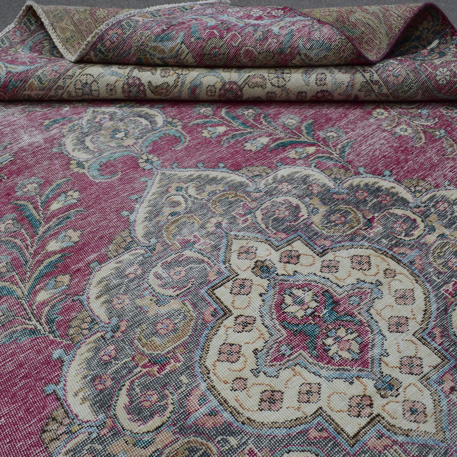 Detailed view of distressed Persian rug pattern with faded rose field and ornamental motifs