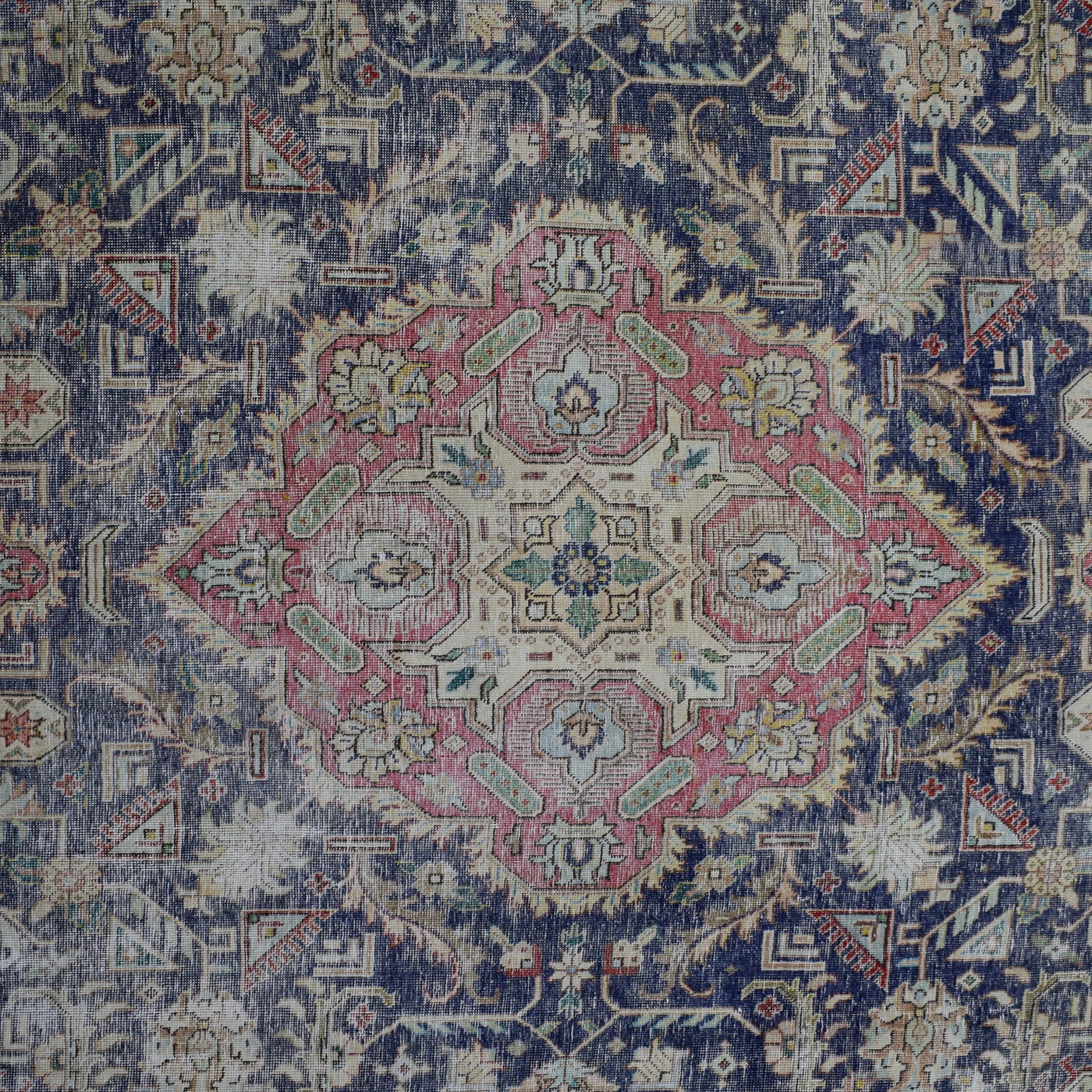 Detailed view of vintage Persian rug medallion featuring geometric floral elements in blue and pink tones