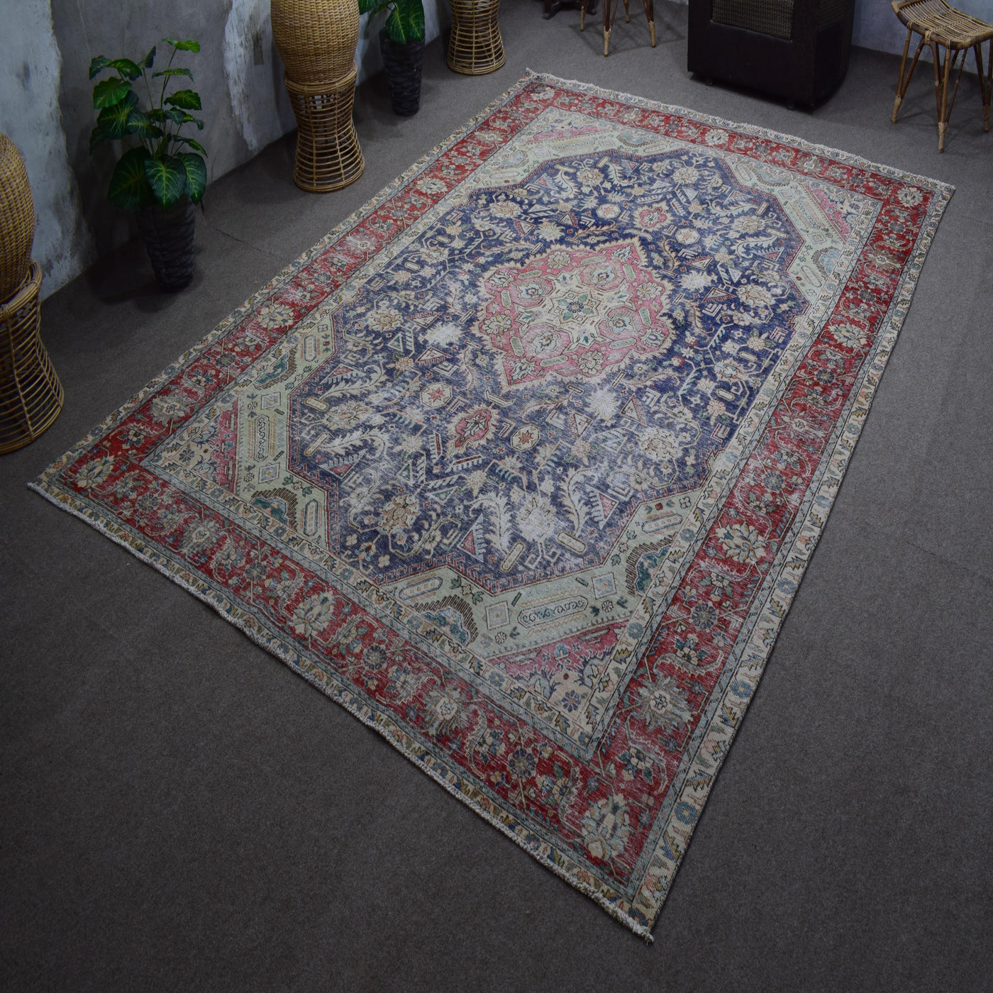 Hand knotted Persian rug photographed at an angle showing overall medallion layout and distressed navy tones