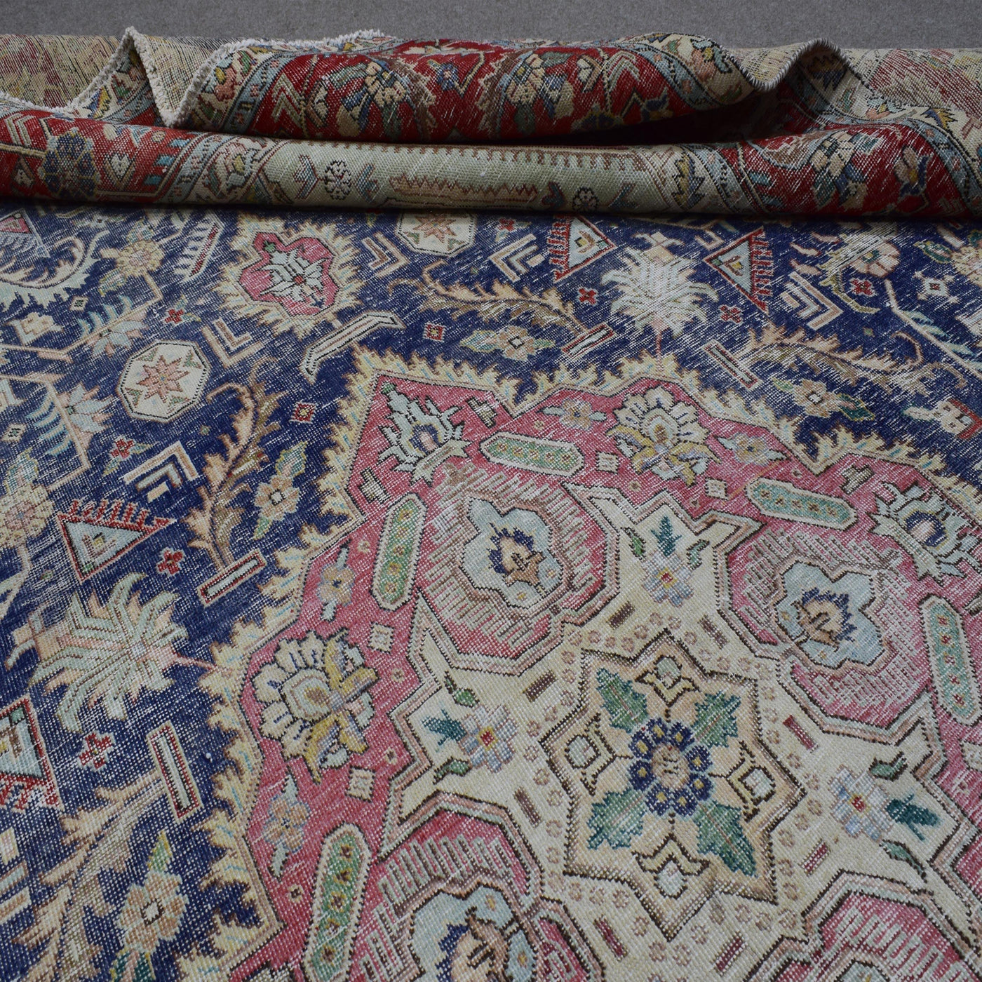 Detailed view of distressed Persian rug pattern with navy field and ornamental floral motifs