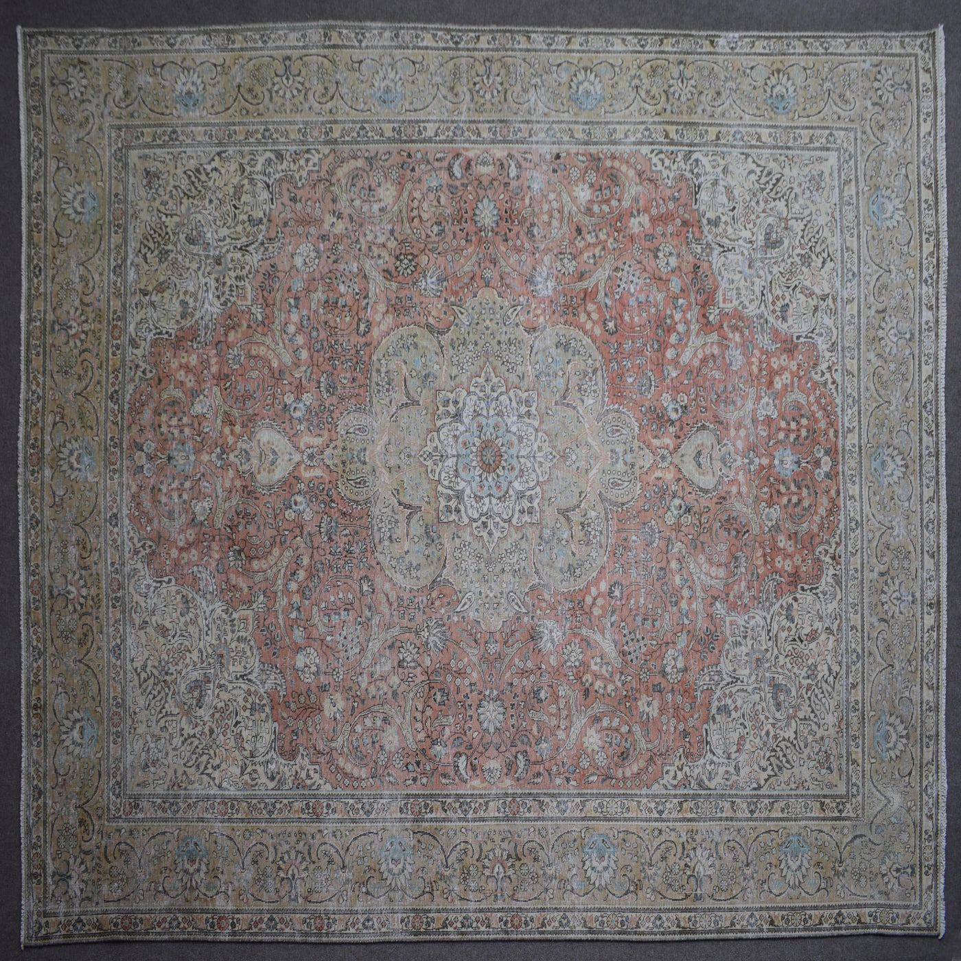 Close up of Persian rug border with floral motifs and intricate guard stripes in soft beige and coral tones