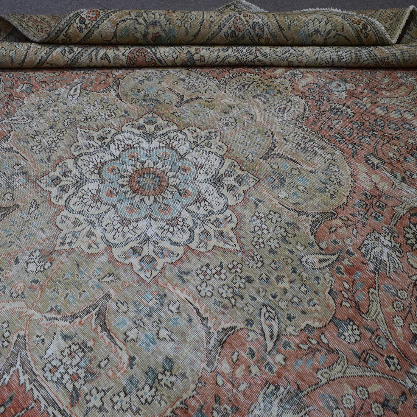 Detailed view of distressed Persian rug pattern with faded coral field and ornamental motifs
