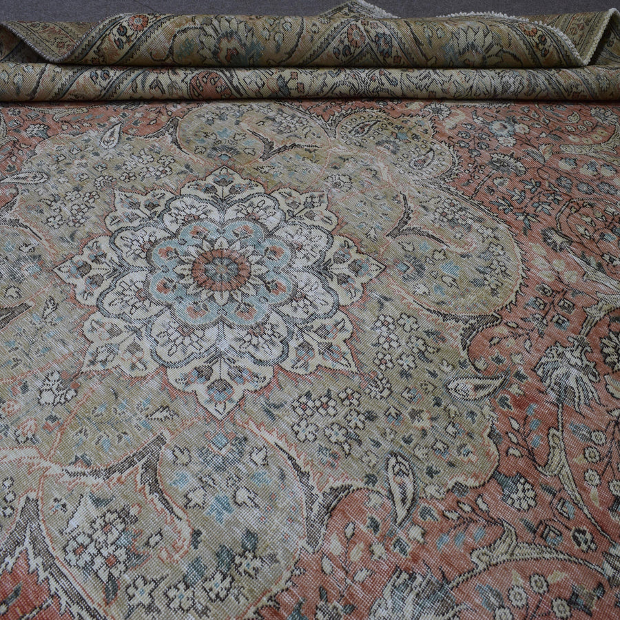 Detailed view of distressed Persian rug pattern with faded coral field and ornamental motifs