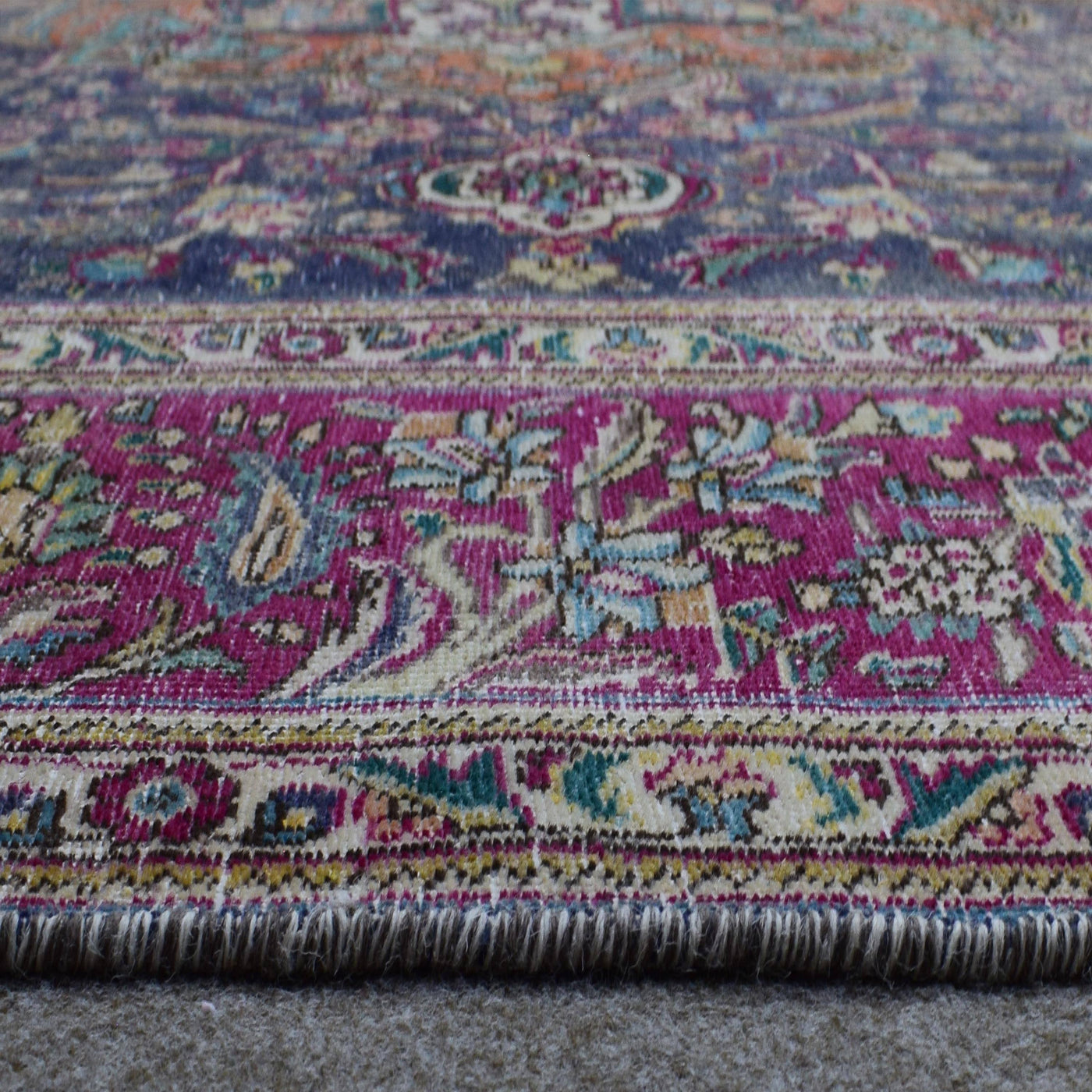 Close up of Persian rug border with vibrant floral motifs and intricate guard stripes
