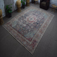 Hand knotted Persian rug photographed at an angle showing overall distressed pattern and medallion layout