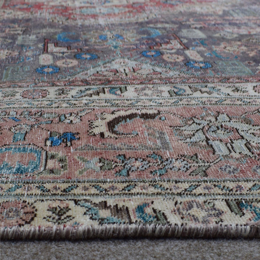 Close up of Persian rug border with colorful floral motifs and intricate guard stripes