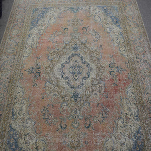 Close up of distressed Persian rug showing ornate central medallion with blue and ivory floral motifs