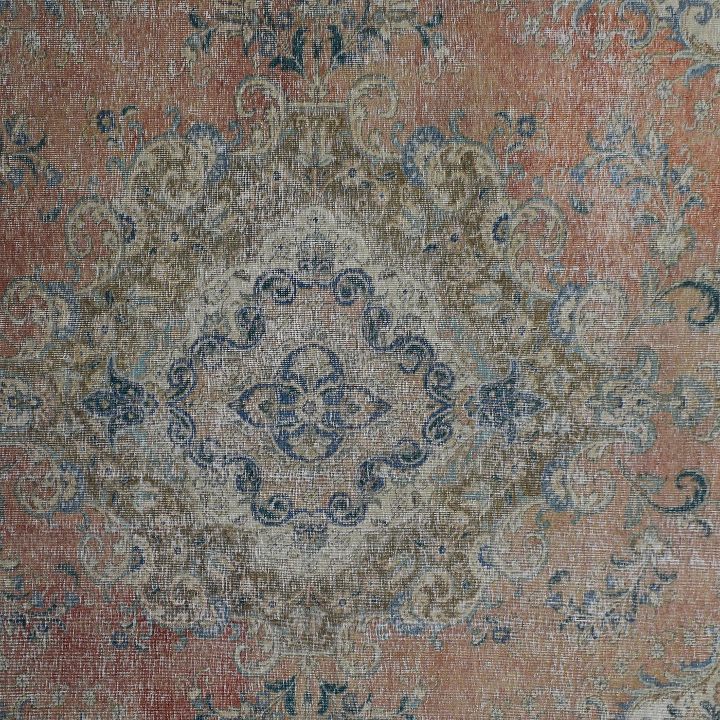 Detailed view of vintage Persian rug pattern featuring intricate floral medallion on coral background