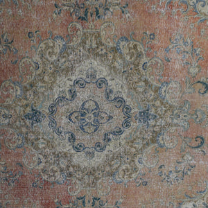Detailed view of vintage Persian rug pattern featuring intricate floral medallion on coral background
