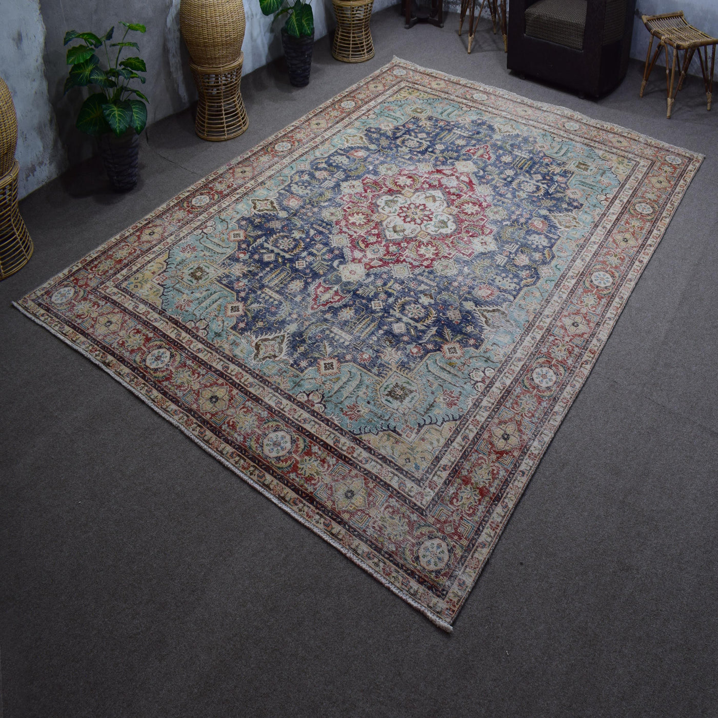 Hand knotted Persian rug photographed at an angle showing overall medallion layout and distressed navy tones